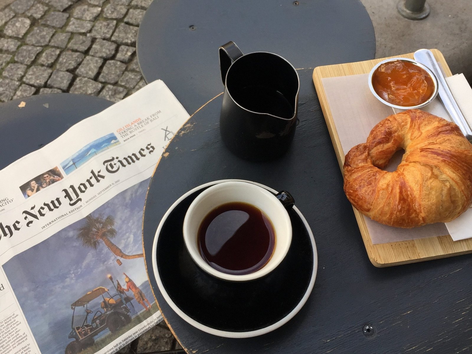 a-cup-of-coffee-on-top-of-newspaper-croissant-on-the-side